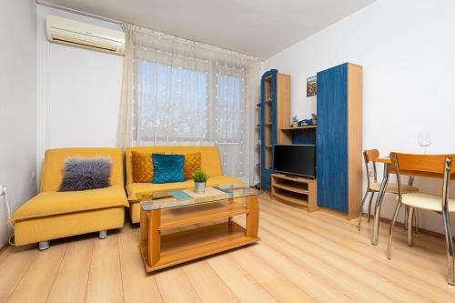 a living room with a yellow couch and a table at Lovely 1BD Apartment close to the Summer Theatre in Plovdiv