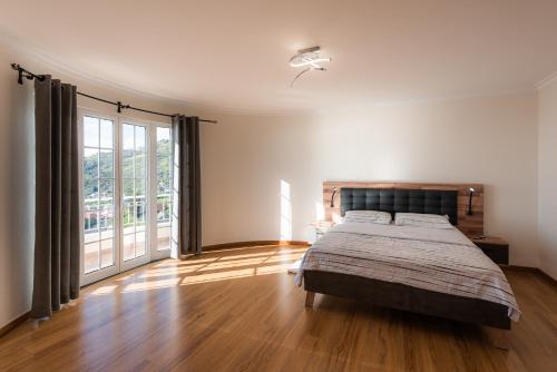 ein Schlafzimmer mit einem Bett und einem großen Fenster in der Unterkunft Sunnyside Villa in Arco da Calheta