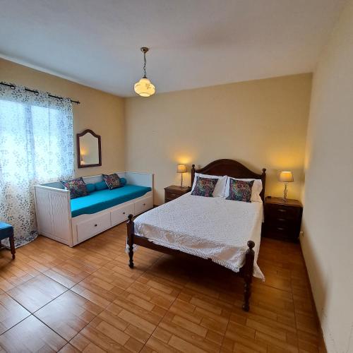 a bedroom with a bed and a couch in it at Chalé Seixal - Sea View in Seixal