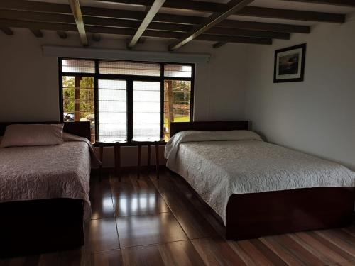 sypialnia z 2 łóżkami i dużym oknem w obiekcie Finca Formentera, este tu pequeño paraíso w mieście Dosquebradas