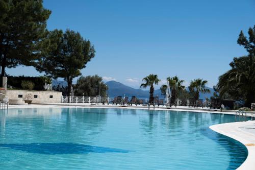 a large swimming pool with chairs and mountains in the background at X Life Hotel Sarıgerme 15 - Adult Hotel in Sarigerme