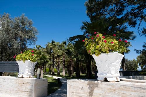 two large white vases with flowers in a park at X Life Hotel Sarıgerme 15 - Adult Hotel in Sarigerme