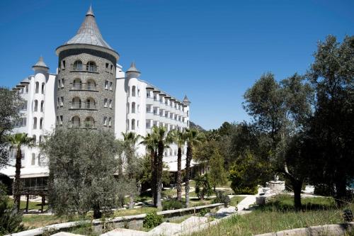 a large white building with a tower in a park at X Life Hotel Sarıgerme 15 - Adult Hotel in Sarigerme