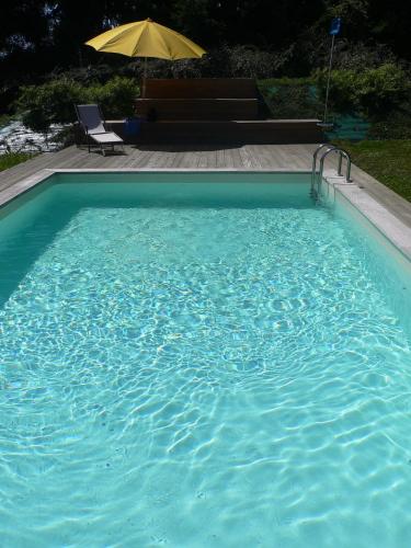 une grande piscine bleue avec une chaise et un parasol dans l'établissement Le Prieuré Boutefol, à Surville