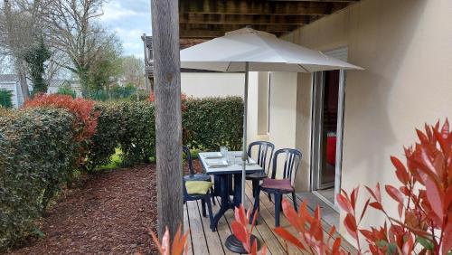 a table and chairs under an umbrella on a patio at T2, 50m du lac, PISCINE, WIFI, jardin terrasse sans vis-à-vis, 1 à 4 pers in Aureilhan