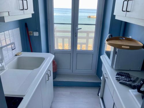 uma casa de banho com um lavatório e uma porta com uma janela em Appartement de standing - avec terrasse et vue mer em Arromanches-les-Bains