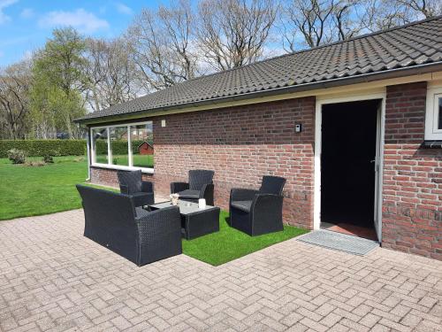 a patio with chairs and a table and a building at 't Brugske in Deurne