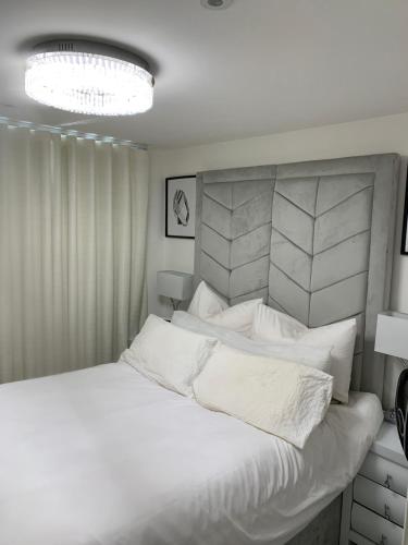 A BYK luxury modern home that sleeps 2 - 8 people في Horndon on the Hill: غرفة نوم بيضاء مع سرير كبير مع وسائد بيضاء