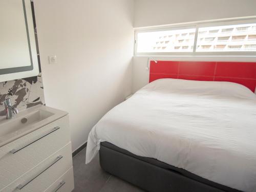 - une chambre avec une tête de lit rouge, un lit et un lavabo dans l'établissement Village Naturiste Coursive Port Nature 2 Vue Mer, au Cap d'Agde