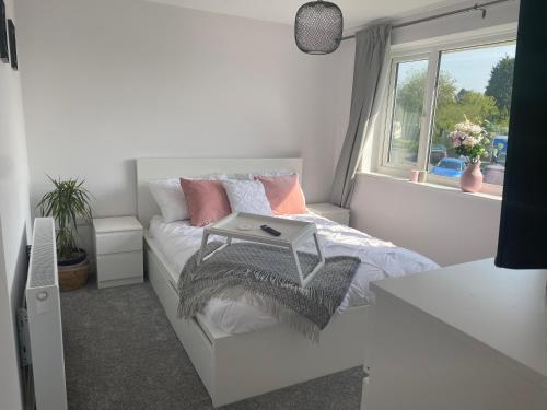 a white bedroom with a bed with a laptop on it at •11 The Nook in Wivenhoe