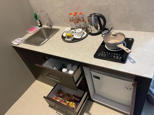 a small kitchen with a sink and a counter top with a stove at Ohana Suites Yogyakarta in Ngabean