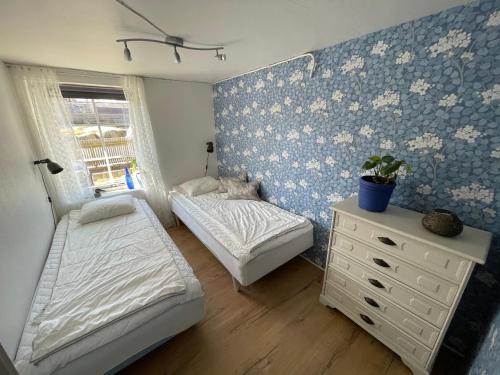 two beds in a bedroom with blue and white wallpaper at 12 Skolgatan in Smögen