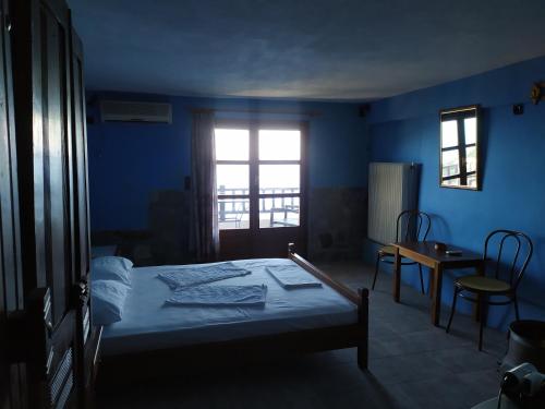 a blue bedroom with a bed and a window at Triple studio apartment in Mylopotamos Beach in Tsagarada