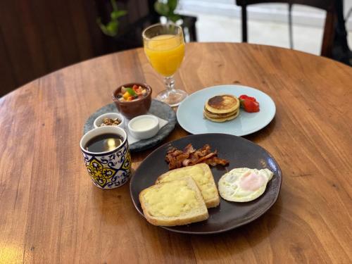 a table with a plate of breakfast food and a glass of orange juice at Casa Versace Salvador - Colonial House in Salvador