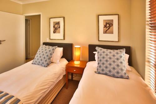 - une chambre avec 2 lits et une table de nuit avec une lampe dans l'établissement Ellefsen Golf Suite 135, Langebaan, 4-sleeper, à Langebaan