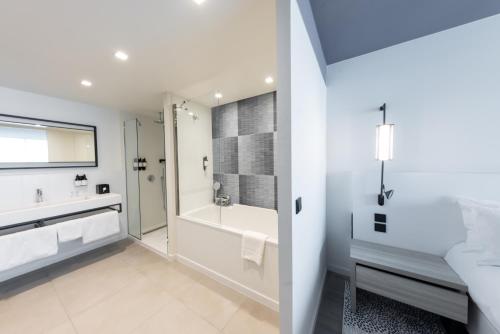 a white bathroom with a tub and a shower at Hotel Indigo Cagnes-sur-Mer by IHG in Cagnes-sur-Mer