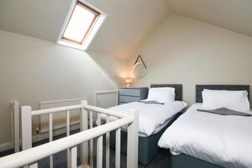 a attic bedroom with two beds and a window at Cottage Style 3 bedroom House - Close to City centre & The Peaks in Chesterfield