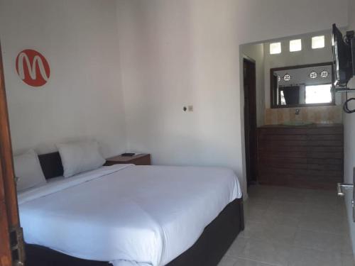 una camera da letto con un grande letto bianco in una stanza di Mugeni Homestay a Senggigi