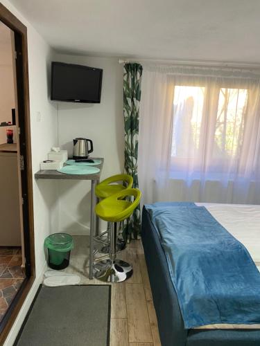 um quarto com uma cama e uma mesa e um banco amarelo em Kaya Home em Sibiu