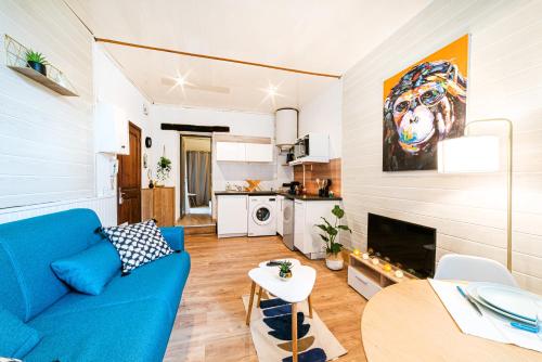 uma sala de estar com um sofá azul e uma cozinha em Centre historique - Cour privée - Arrivée autonome em Agen
