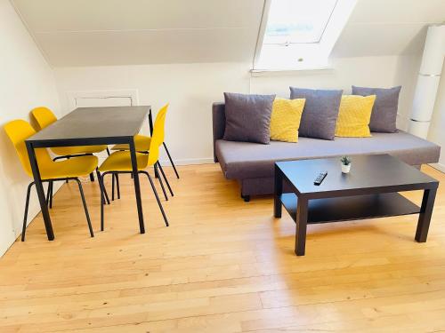 uma sala de estar com um sofá, uma mesa e cadeiras em aday - Reberbansgade Apartment Suite em Aalborg