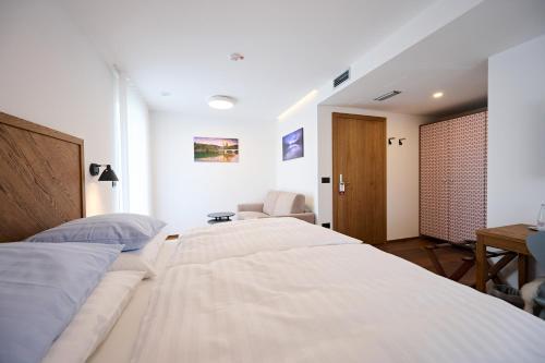 a white bedroom with two beds and a chair at Hiša Ančka, Šenčur - 3 min to the Airport in Šenčur