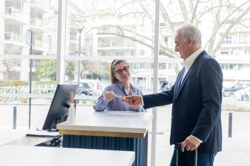 a man shaking hands with a woman at a desk at Hotel Indigo Cagnes-sur-Mer by IHG in Cagnes-sur-Mer