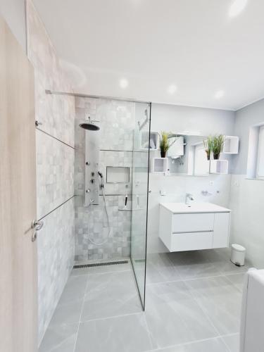 a white bathroom with a shower and a sink at Apartman Joki in Novi Vinodolski