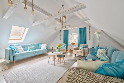 salon z niebieskimi kanapami i stołem w obiekcie Dom & House - Apartament Orłowskie Molo przy plaży z widokiem na morze w mieście Gdynia