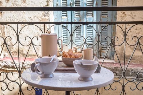a table with two cups and a bowl of food on a balcony at Casa Livieres in Chania Town