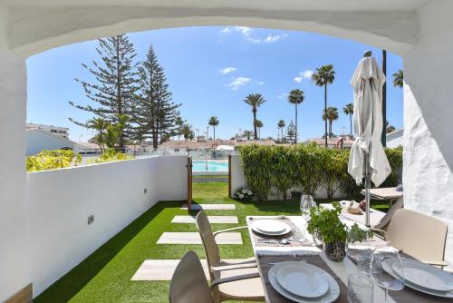 a patio with a table and chairs and a pool at Bungalow Santa Barbara EMC2 by VillaGranCanaria in Playa del Ingles