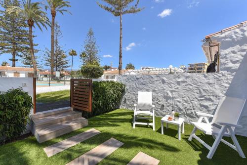 a lawn with two chairs and a table and a staircase at Bungalow Santa Barbara EMC2 by VillaGranCanaria in Playa del Ingles