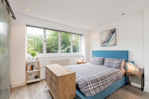 a bedroom with a blue bed and a window at Luxury Architect Designed Apt 13 Mins to Royal mile in Edinburgh