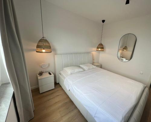 sypialnia z białym łóżkiem i lustrem w obiekcie The ONE By Moro w mieście Vantačići