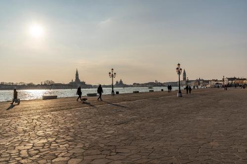 a group of people walking on a street next to the water at Residenza La Duchessa Deluxe Rooms in Venice