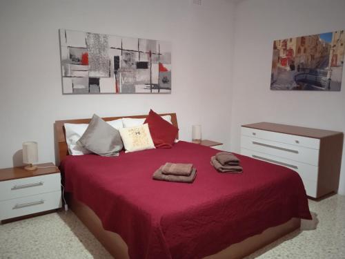 a bedroom with a red bed with two towels on it at University Area Msida in Msida