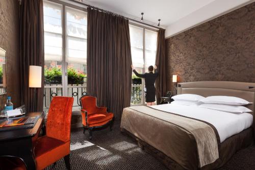 a woman is looking out the window of a hotel room at Le Pavillon de la Reine & Spa, Place des Vosges in Paris