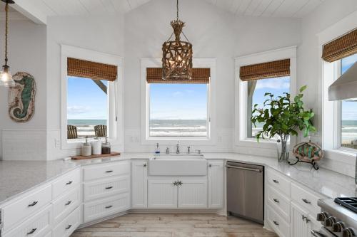 een keuken met witte kasten, een wastafel en ramen bij Sunrise, Sunburn, Sunset, Repeat home in Stingaree