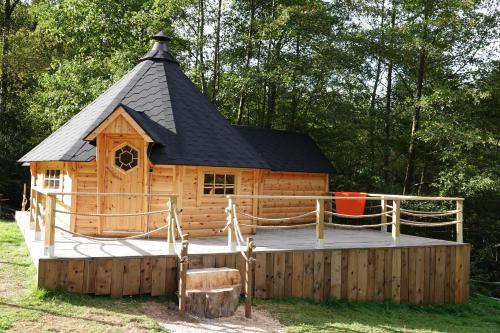 eine große Holzhütte mit schwarzem Dach in der Unterkunft Le Kota Etable in La Chapelle