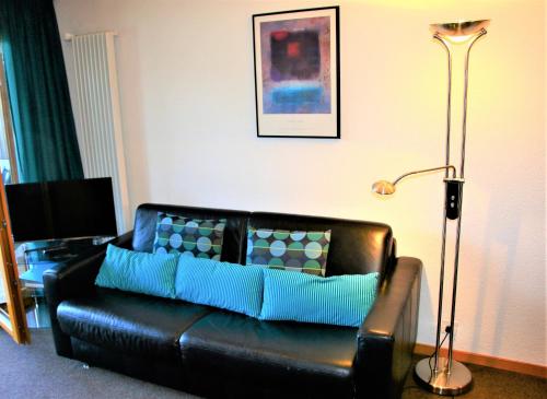 un sofá de cuero negro en una sala de estar con lámpara en Greppons COSY & MOUNTAIN apartments by Alpvision Résidences, en Veysonnaz