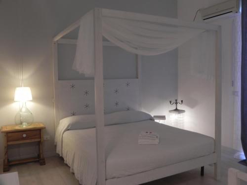 Cama blanca con dosel en un dormitorio blanco con lámpara en Gea Apartment Etna, en Nicolosi