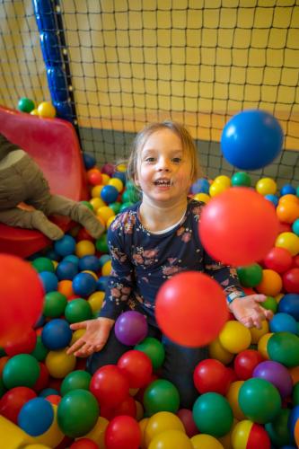 a little girl sitting in a pile of balls at Familotel Mein Krug in Warmensteinach