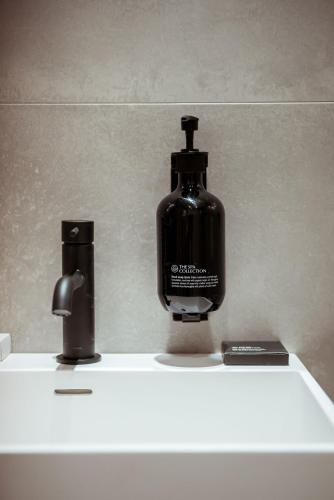 a black bottle of soap sitting on top of a sink at Boutique Hotel Restaurant BAL in Echteld