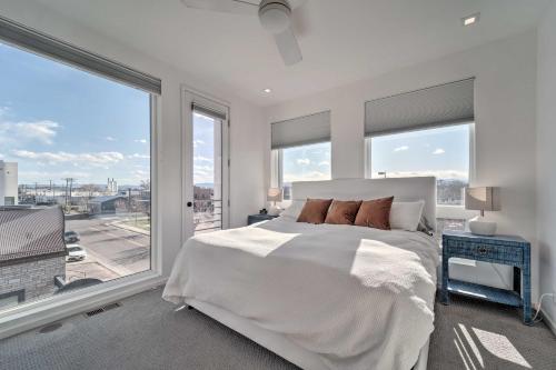 a bedroom with a large white bed and large windows at Sleek Townhouse with Rooftop Patio and Mtn Views! in Denver