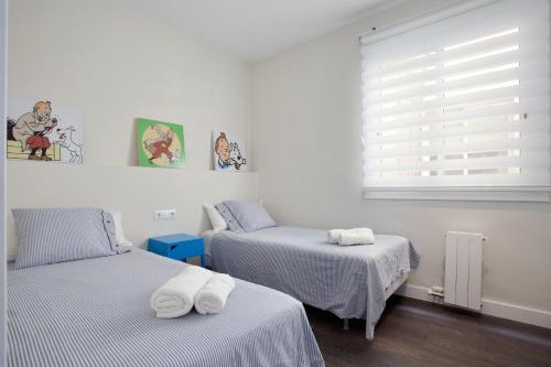 two twin beds in a room with a window at Consell de Cent Apartment in Barcelona