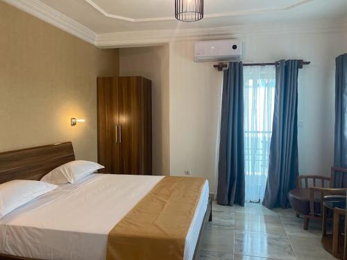 a bedroom with a large bed with blue curtains at Hotel Residence La Corniche in Dakar