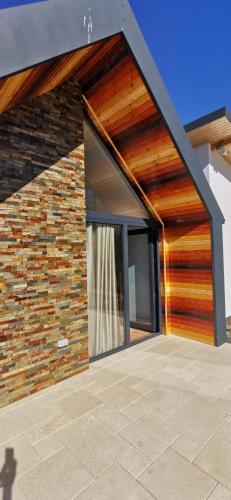 a house with wooden doors and a brick wall at Pastravaria Zavoi in Valea Danului