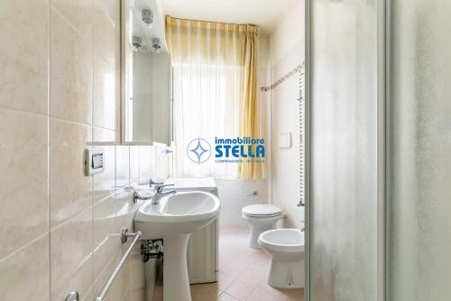 Baño blanco con lavabo y aseo en Condominio Corallo, en Lido di Jesolo