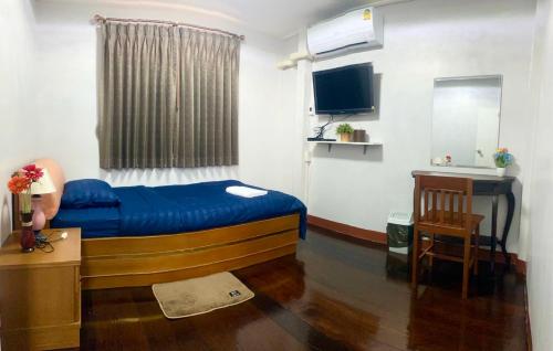 a small room with a blue bed and a desk at The Best House&Hostel in Ban Don Muang