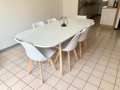- une table à manger blanche avec des chaises blanches dans l'établissement La maison de ville - 4 chambres, 2 sdb, terrasse et garage - 90m2, à Vesoul